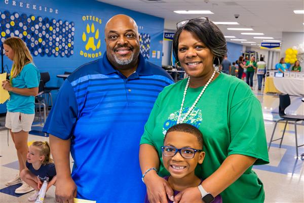 family including Principal smiling inside school